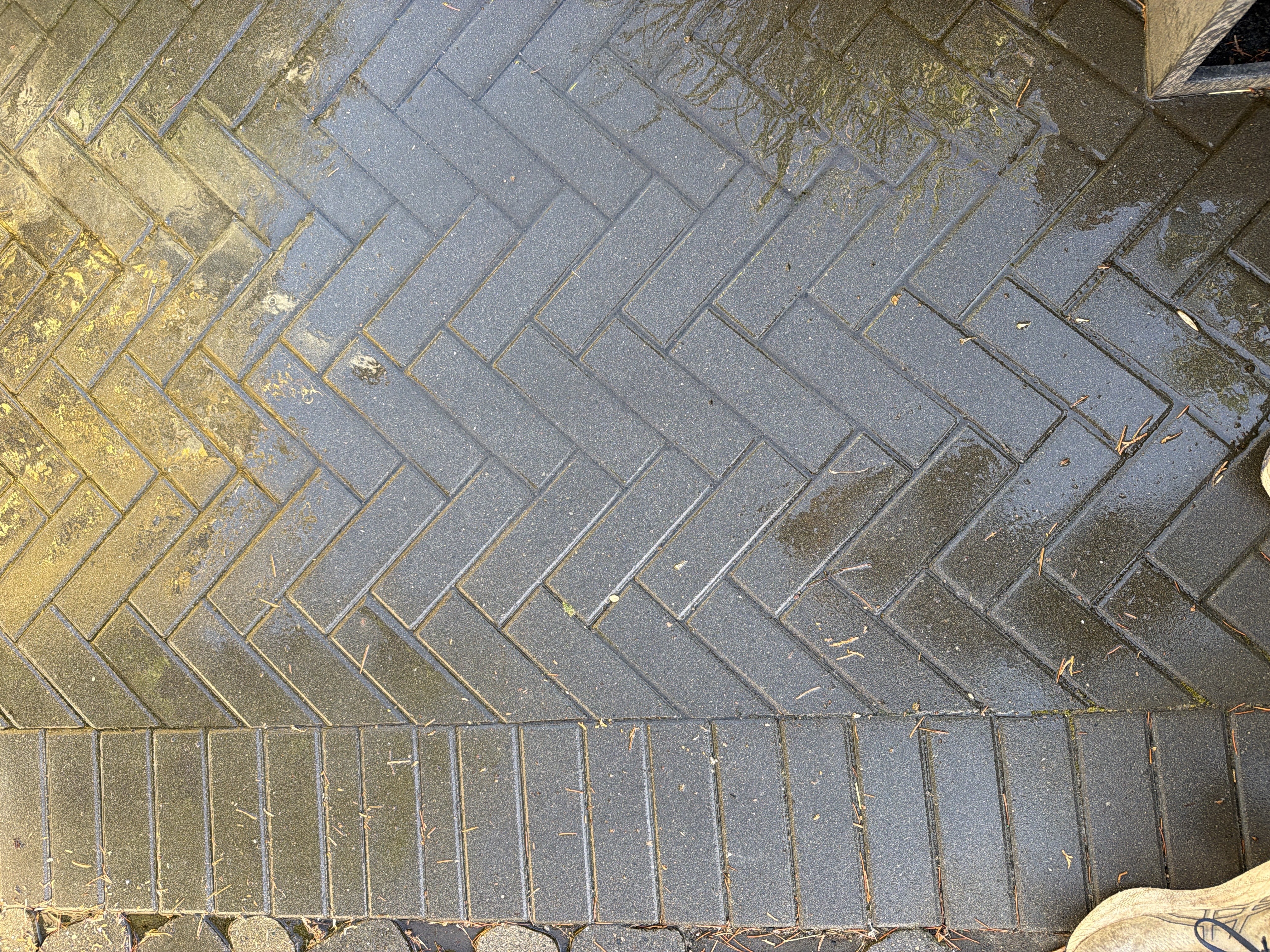 Dark rectangular pavers laid diagonally in herringbone beside a straight border.