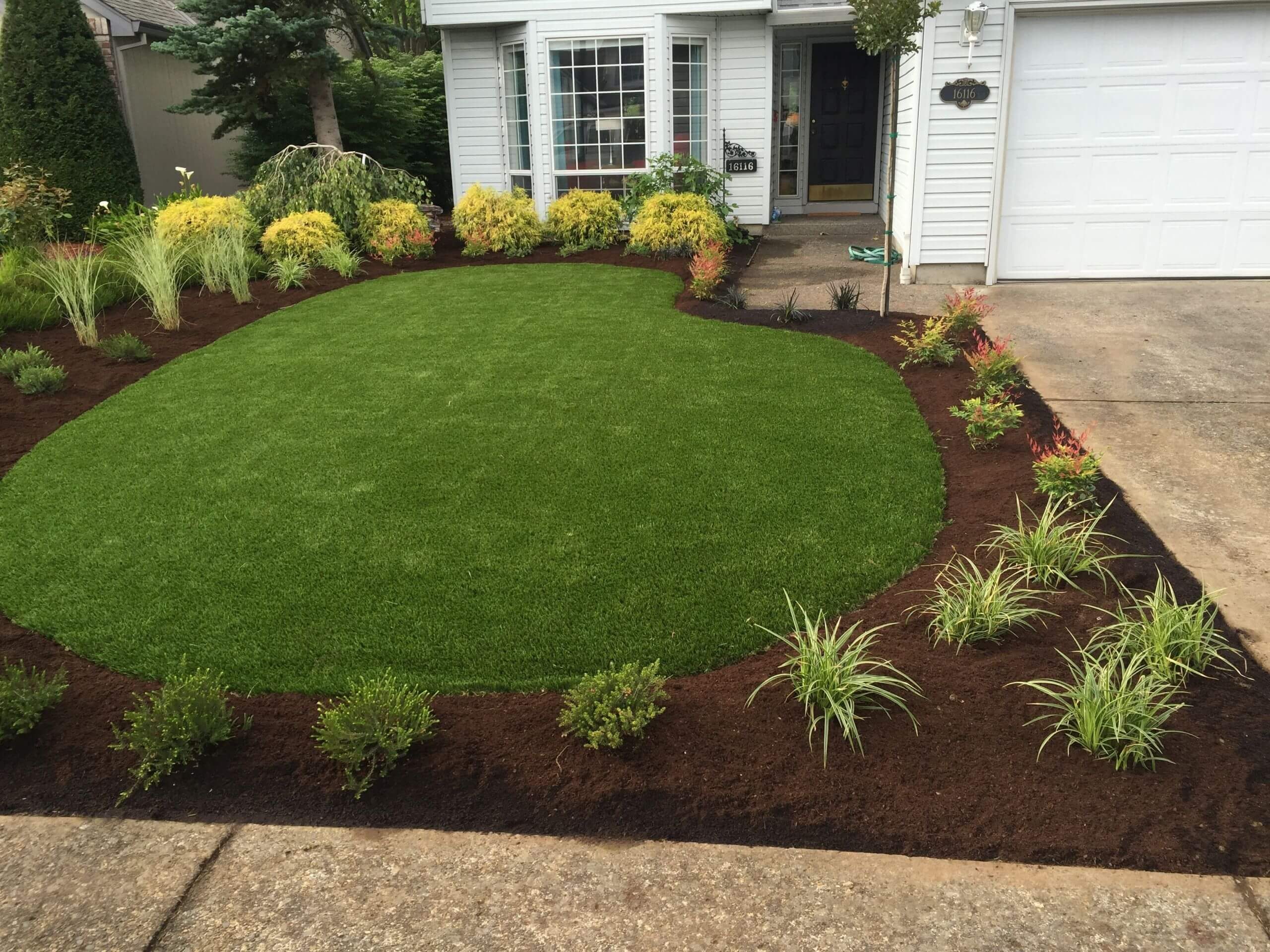 Artificial turf surrounded by curved planting beds in a Shovel & Thumb project